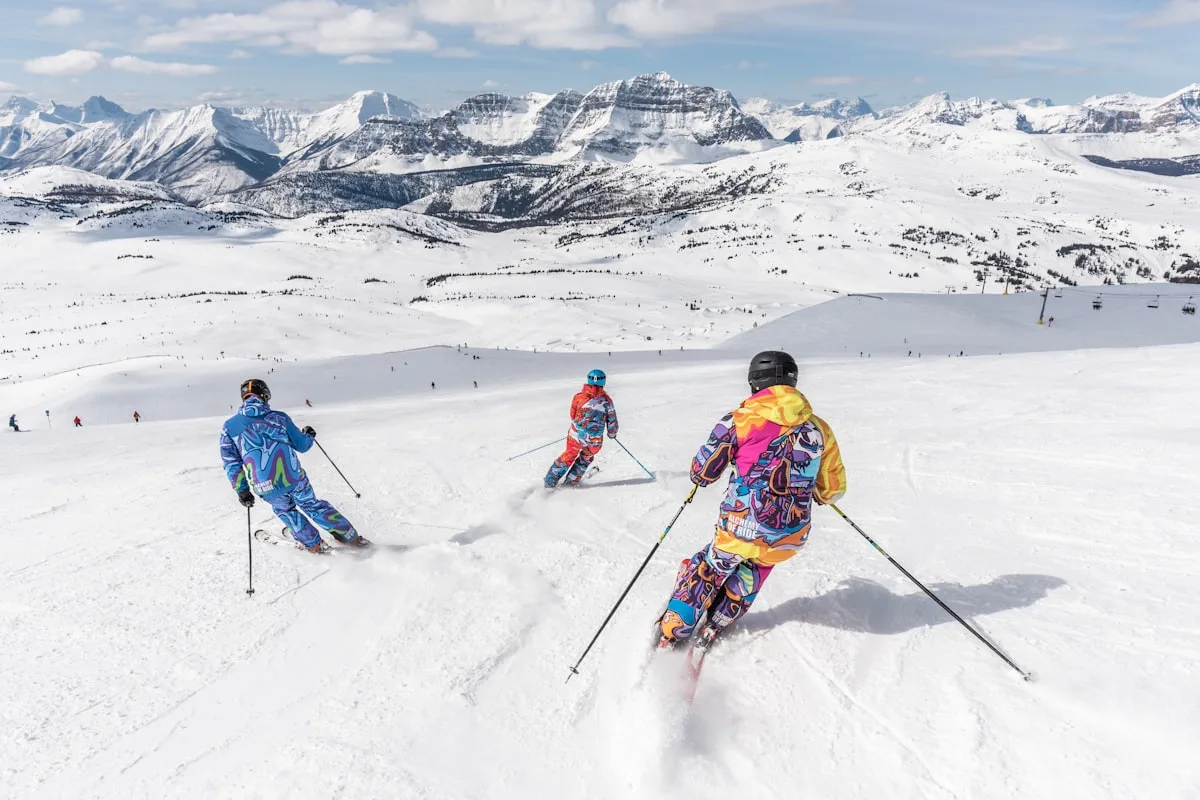 Skiers on a snowy Alpine piste under clear sky